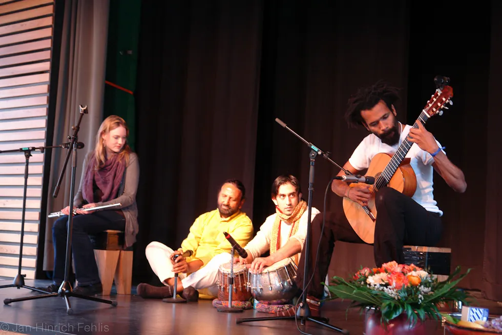 Satish Joshi Kumar mit Musikern an Gitarre und Tabla auf der Bühne