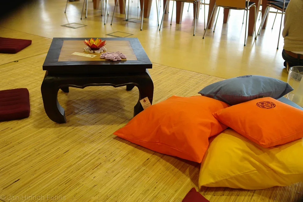 Bunte Sitzkissen und ein kleiner Holztisch auf dem Saalboden