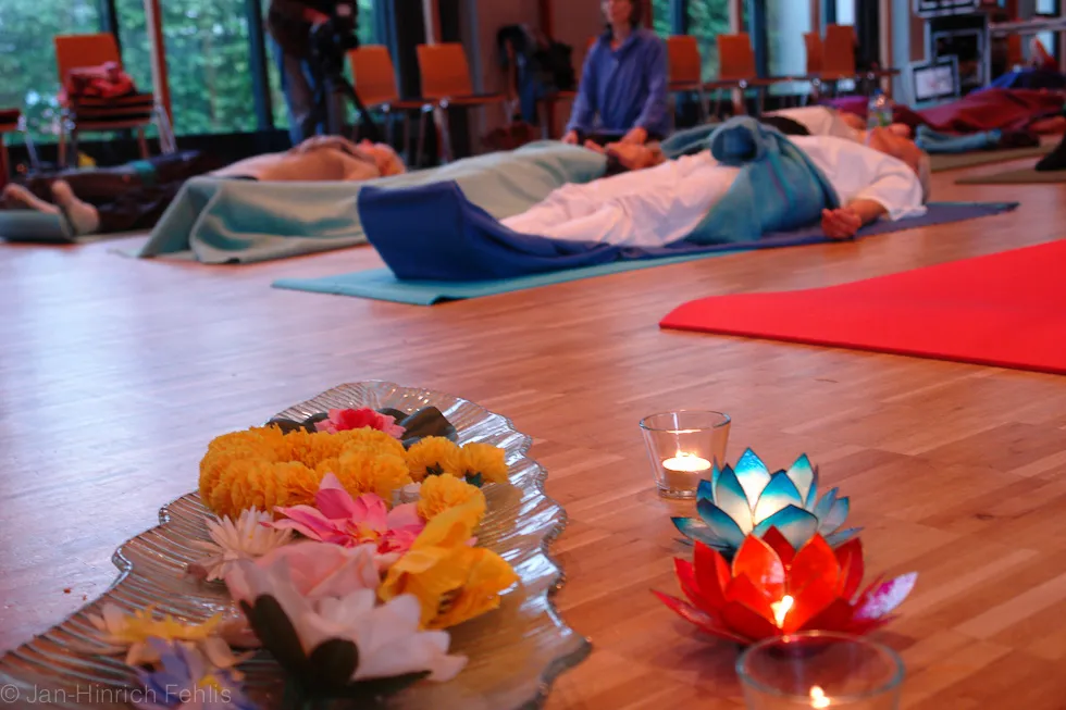 Entspannung auf der Matte mit Blüten und Kerzenlicht