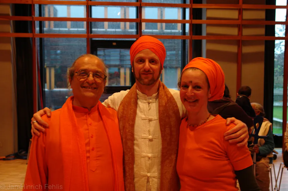 Drei Gäste in Orange posieren lachend für ein Foto